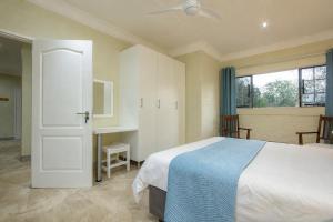 a bedroom with a bed and a desk and a window at Kruger's Retreat & Rest in Marloth Park