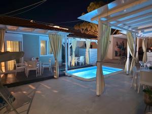 a swimming pool with a pergola and a table and chairs at ΑVLI Sarti Studios & Apartments no 3 in Sarti