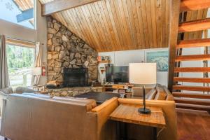 a living room with a couch and a stone fireplace at Chalet 15 by Mammoth Mountain Chalets in Mammoth Lakes