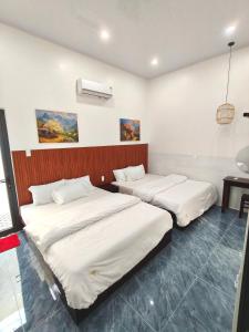 two beds in a room with white sheets at Cherry House villa in Hà Tiên