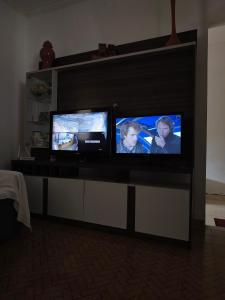 two televisions sitting on a entertainment center at Casa ampla in Muriaé
