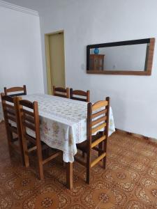 a dining room table with four chairs and a mirror at Casa ampla in Muriaé