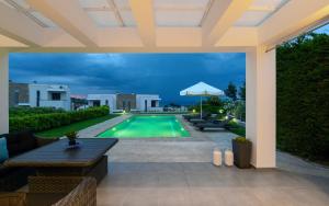 an outdoor patio with a pool and an umbrella at Pentanemi Luxury Villa in Hanioti