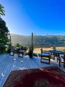 a deck with tables and chairs and a view at Villa Sol - Wilderness in Wilderness