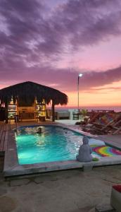 a swimming pool with a straw umbrella and the ocean at Casa Villa Alive - Vichayito Sur, Los Organos Talara in San Martín