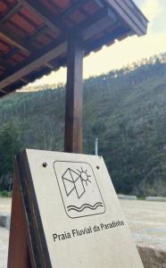 a sign on a post in front of a mountain at Casa da Azenha- Riverside Retreat by Paiva River Beach in Paradinha