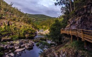 a bridge over a river next to a mountain at Casa da Azenha- Riverside Retreat by Paiva River Beach in Paradinha