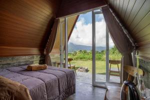 a bedroom with a bed and a large window at Pandawa Glamping Kintamani in Bangli