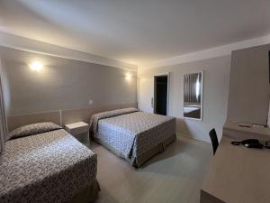 a hotel room with two beds and a table at Atibaia Residence Hotel & Resort in Atibaia