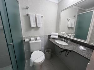 a bathroom with a toilet and a sink and a mirror at Atibaia Residence Hotel & Resort in Atibaia