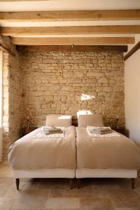 a bedroom with two beds in front of a stone wall at La Petite Noble in Commentry +29 photos