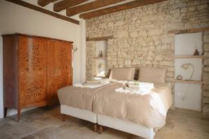 a bedroom with a large bed and a stone wall at La Petite Noble in Commentry