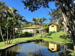 a garden with a pond in front of a house at Pousada Primavera in São Luiz do Paraitinga