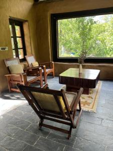 a room with chairs and a table and a window at Sarayu Farmstays in Manāli