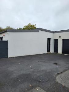 a white building with two doors and a parking lot at Maison Fabien in Surzur +3 photos