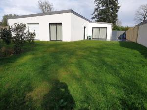 a white house on a yard with a green lawn at Maison Fabien in Surzur
