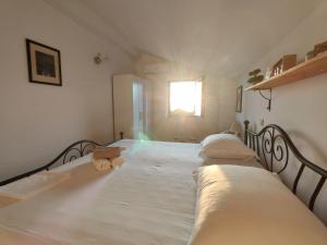a bedroom with two beds with white sheets and a window at Holliday home Alida with jacuzzi in Podgora