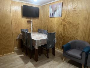 a dining room with a table and chairs and a tv at Casa Amayita in Puerto Varas