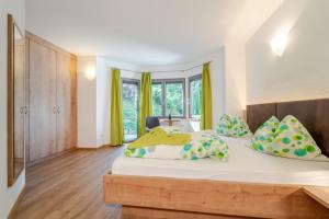 a bedroom with a bed with yellow and green pillows at Residence Passerhaus in Schenna