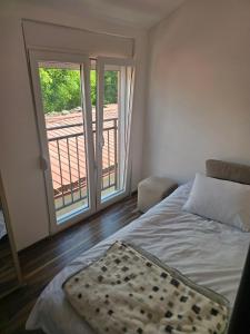 a bedroom with a bed and a balcony at Gintas Comfort in Podgorica