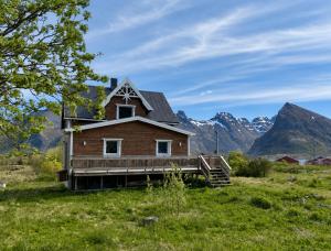 a house in a field with mountains in the background at The Chess House Lofoten - Luxury Arctic Villa in Fredvang in Fredvang