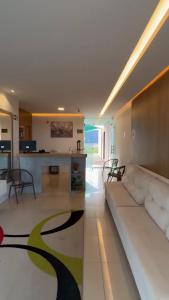 a living room with a white couch and a kitchen at Hotel Califórnia in Canindé