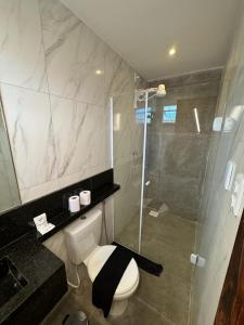 a bathroom with a toilet and a glass shower at Hotel Califórnia in Canindé