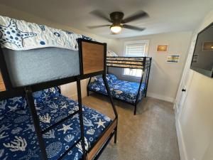 two bunk beds in a room with a ceiling fan at Sun2Sand Beach House in Salisbury