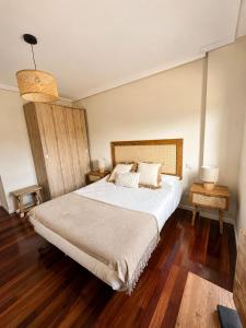 a bedroom with a large white bed and wooden floors at Apartamento Guou in Comillas +14 photos