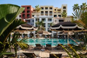 a swimming pool with chairs and umbrellas and buildings at Bahia Principe Escape Tenerife - Hyatt Inclusive Collection in Adeje +39 photos
