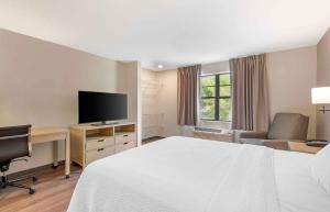 a hotel room with a bed and a desk with a television at Extended Stay America Suites - St Petersburg - Clearwater - Executive Dr in Clearwater