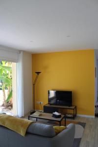 a living room with a couch and a yellow wall at Vue sur les Pyrénées in Madiran