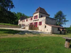 an old building with red windows on a field at La truffière in Belvès