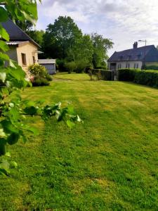 a yard with a house and green grass at Au cerisier in Saint-Maulvis