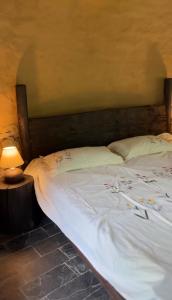 a large white bed with a wooden headboard next to a lamp at Sarayu Farmstays in Manāli