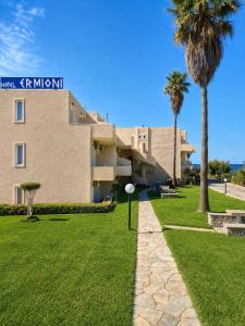 a building with palm trees and a walkway at Ermioni Hotel in Georgioupolis
