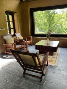 a room with chairs and a table and a window at Sarayu Farmstays in Manāli