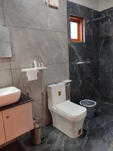 a bathroom with a white toilet and a sink at Aruvi on the cliff in Varkala +9 photos
