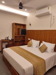 a bedroom with a large bed and a television at Aruvi on the cliff in Varkala