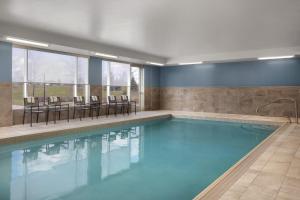 a pool with chairs and tables in a building at Holiday Inn Express & Suites - Aurora by IHG in Aurora