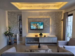 a living room with a couch and a tv on a wall at The Lake Haus Cebu in Lapu Lapu City