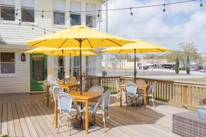 a wooden deck with tables and chairs with yellow umbrellas at The Parrish Grove Inn in Cocoa