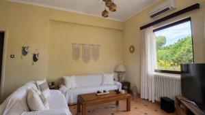 a living room with a white couch and a window at Sounio Garden Retreat in Panayía