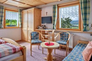 a small room with a desk with a tv and chairs at Haus Schmid in Lenzkirch