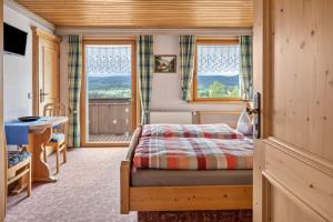 a bedroom with a bed and a table and windows at Haus Schmid in Lenzkirch