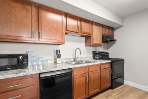 a kitchen with wooden cabinets and a black dishwasher at Newly Renovated Unit in Central Spfld #101 in Springfield