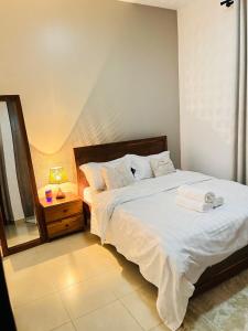 a bedroom with a bed and a night stand with a mirror at ValdOrea Residences in Entebbe