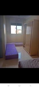 a bedroom with a purple bed and a window at Saïdafriends in Saïdia