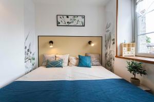 a bedroom with a large bed with blue pillows at Maison de La Beslière meublé de tourisme 2 étoiles in Folligny