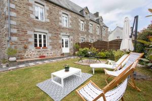 a patio with two chairs and a table and a white table at Maison de La Beslière meublé de tourisme 2 étoiles in Folligny